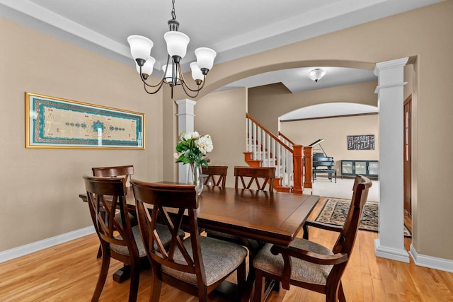 dining room with light wood finished floors, decorative columns, arched walkways, and baseboards