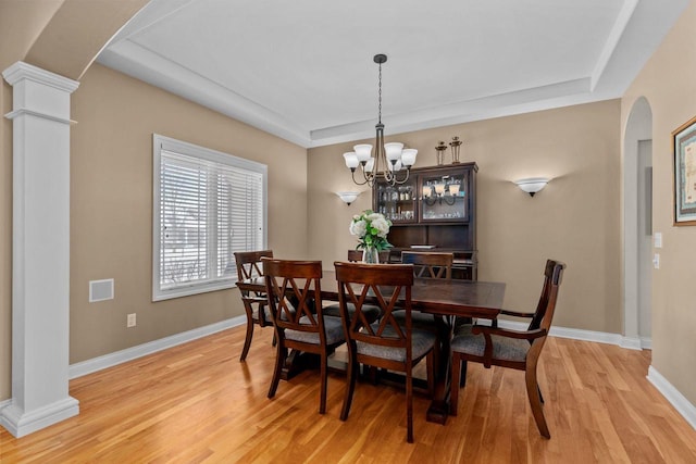 dining space with arched walkways, baseboards, decorative columns, and light wood finished floors