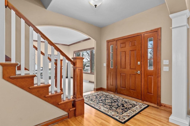 foyer featuring arched walkways, baseboards, wood finished floors, and ornate columns