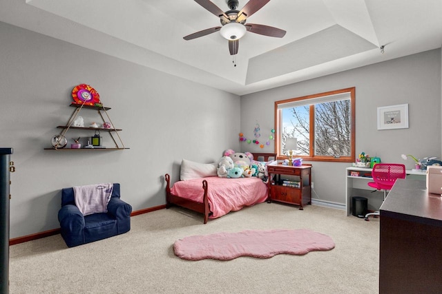 carpeted bedroom with baseboards, a tray ceiling, and ceiling fan