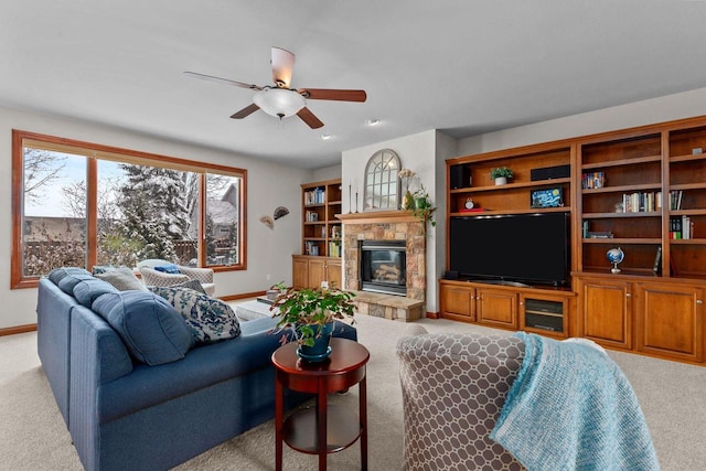 living room featuring a ceiling fan, baseboards, carpet flooring, and a glass covered fireplace