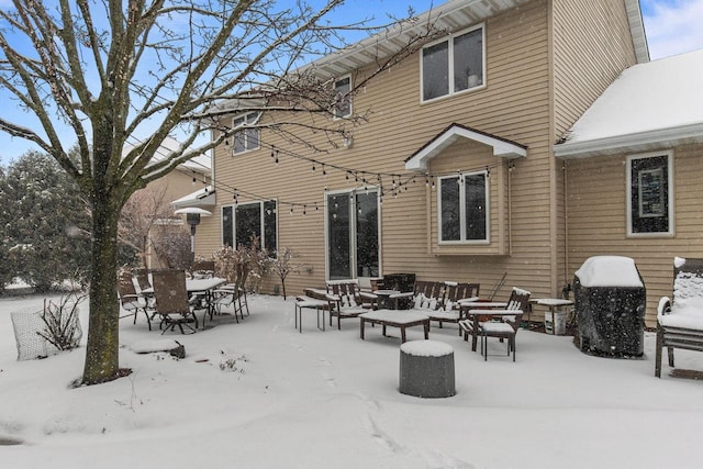 snow covered property with outdoor dining space, a patio, and an outdoor living space