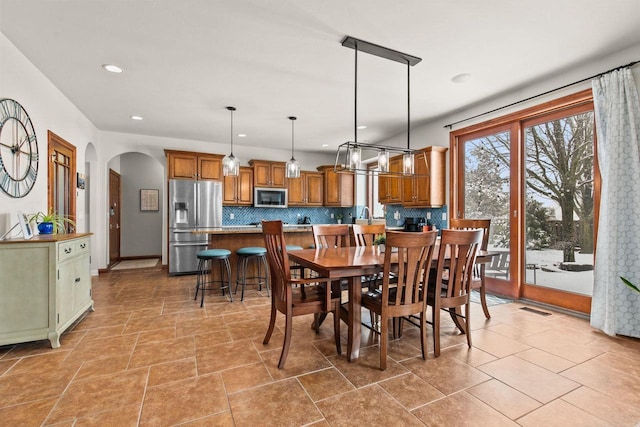 dining room featuring arched walkways, visible vents, baseboards, and recessed lighting