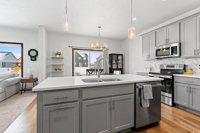 kitchen featuring appliances with stainless steel finishes, plenty of natural light, a sink, and gray cabinetry