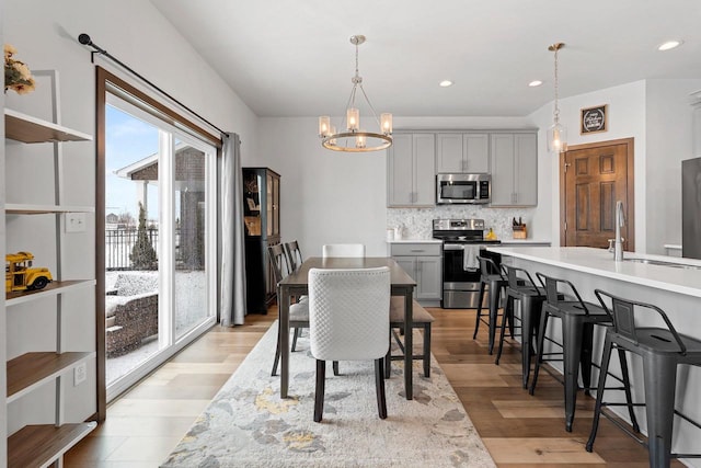 dining area with a notable chandelier, light wood-style flooring, and recessed lighting