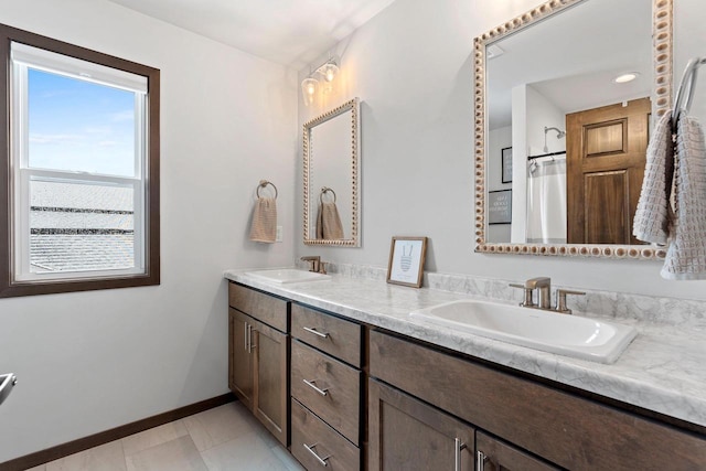 bathroom featuring double vanity, tile patterned flooring, baseboards, and a sink