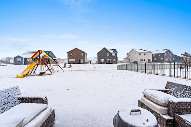 yard covered in snow featuring a fenced backyard, a residential view, and a playground