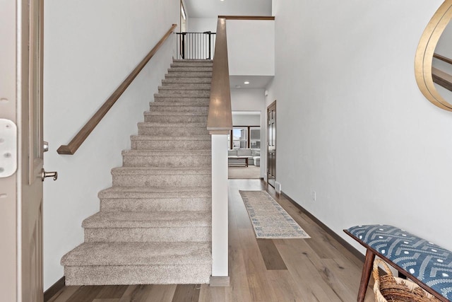 stairs featuring baseboards, a high ceiling, and wood finished floors