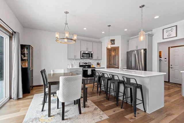 dining space with a notable chandelier, light wood finished floors, and recessed lighting