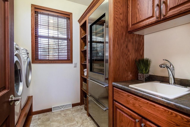 laundry room with a sink, visible vents, baseboards, washer and dryer, and cabinet space