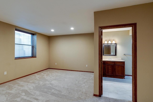 spare room featuring recessed lighting, light colored carpet, a sink, and baseboards