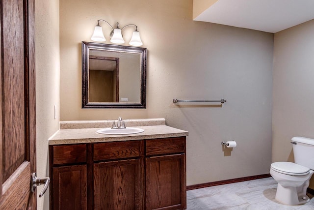 half bath with toilet, baseboards, and vanity