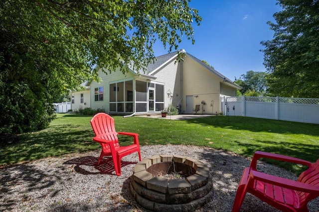 rear view of property with a sunroom, an outdoor fire pit, a patio area, and a lawn