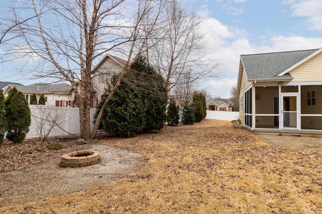 view of yard featuring a sunroom, an outdoor fire pit, and fence