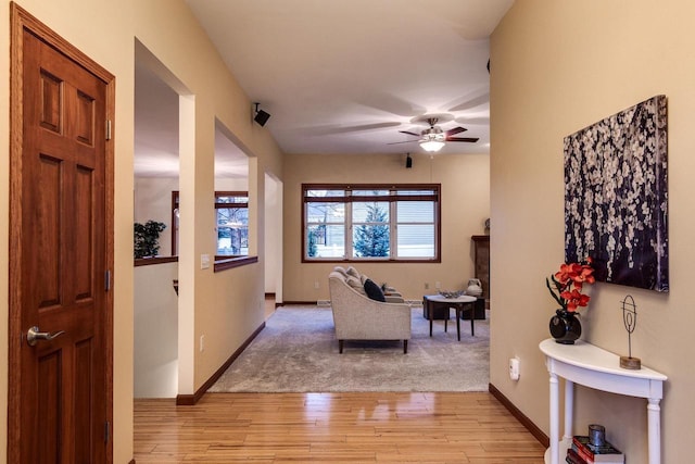 living area with light wood finished floors, baseboards, and a ceiling fan