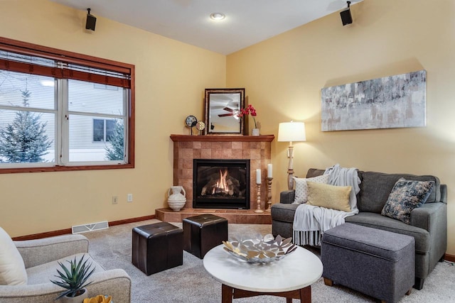 carpeted living area featuring baseboards, visible vents, and a tile fireplace