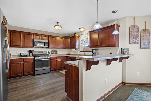 kitchen with a peninsula, dark wood-style floors, appliances with stainless steel finishes, and a breakfast bar area