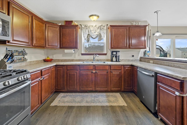 kitchen featuring stainless steel appliances, light countertops, a sink, and dark wood finished floors