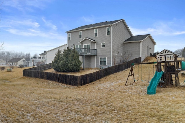 back of house with a playground and fence