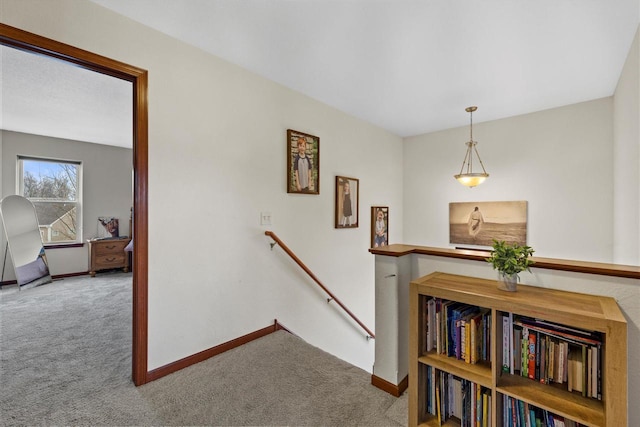 hall with carpet flooring, an upstairs landing, and baseboards