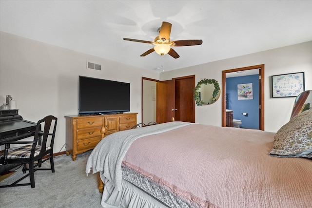 bedroom featuring light carpet, visible vents, baseboards, ceiling fan, and ensuite bathroom