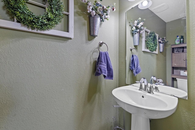 bathroom featuring a textured wall and a sink