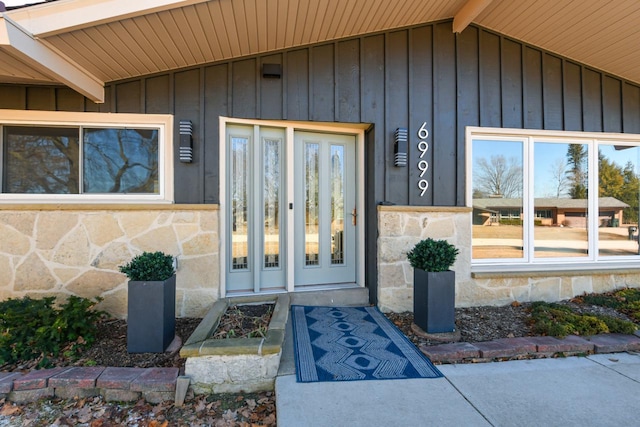 view of exterior entry with stone siding and board and batten siding