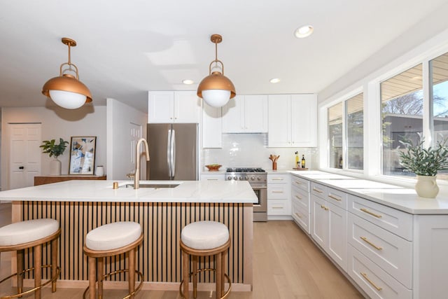 kitchen featuring decorative backsplash, appliances with stainless steel finishes, light wood-style floors, white cabinets, and a sink