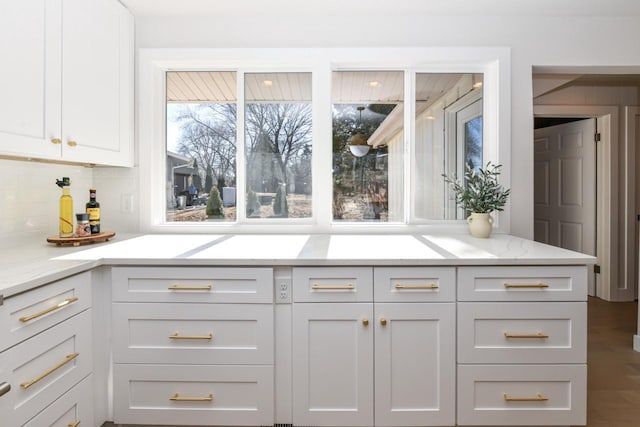 kitchen with tasteful backsplash, light stone countertops, and white cabinets