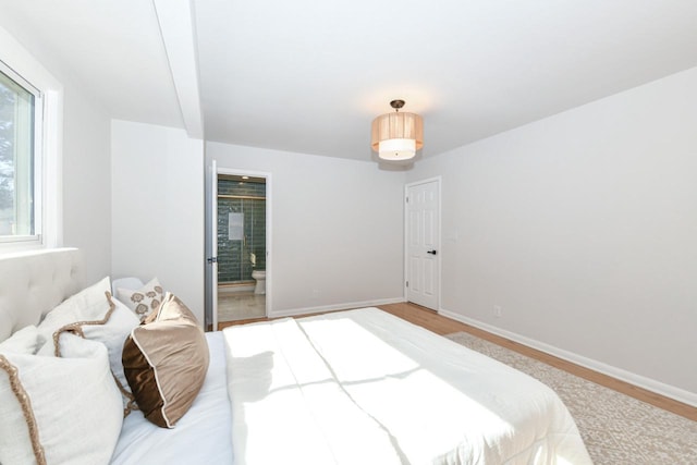 bedroom with light wood-style flooring, baseboards, and ensuite bathroom