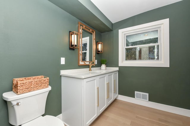 bathroom with baseboards, visible vents, toilet, wood finished floors, and vanity