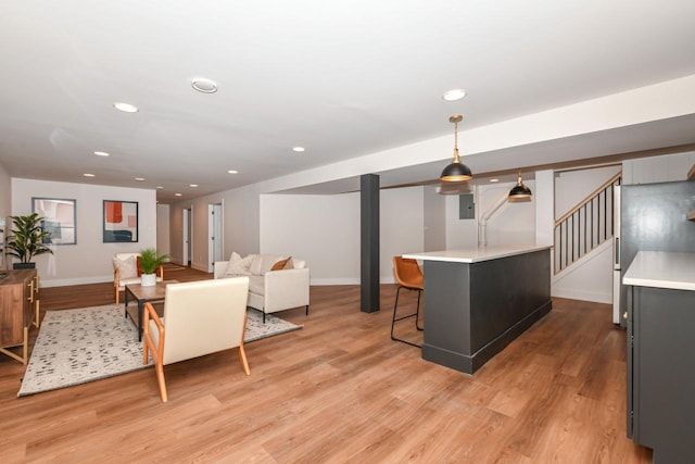 living area featuring light wood-style floors, recessed lighting, baseboards, and stairs