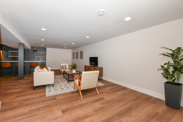 living area with a bar, light wood-style flooring, baseboards, and recessed lighting