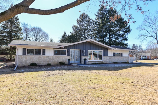 ranch-style home with stone siding, board and batten siding, and a front yard