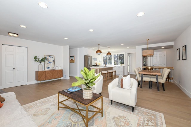 living room featuring light wood-type flooring, baseboards, and recessed lighting