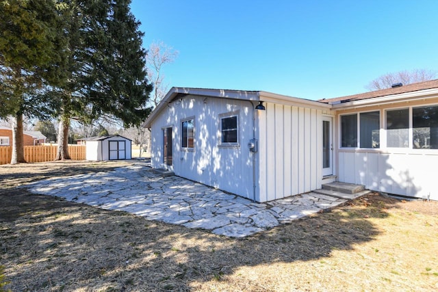 view of side of property with a storage unit, fence, board and batten siding, and an outdoor structure