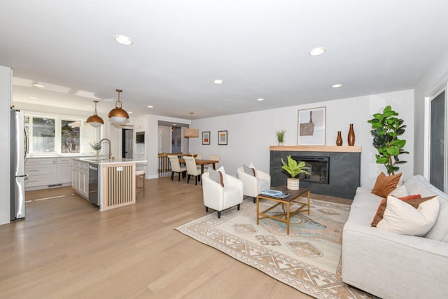 living area with a glass covered fireplace, light wood-style flooring, and recessed lighting