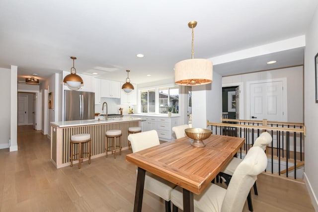 dining space featuring baseboards, light wood-style flooring, and recessed lighting