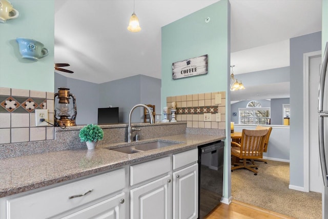 kitchen featuring decorative backsplash, dishwasher, light stone counters, white cabinetry, and a sink