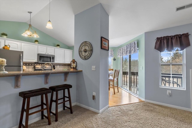 kitchen with light carpet, visible vents, a breakfast bar, stainless steel appliances, and white cabinetry