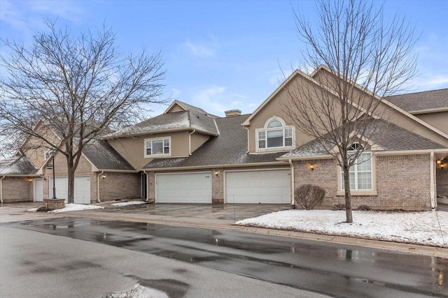 view of front of house featuring an attached garage, stucco siding, concrete driveway, and brick siding