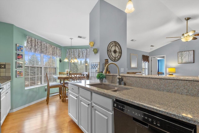 kitchen with a sink, visible vents, black dishwasher, vaulted ceiling, and light wood-type flooring