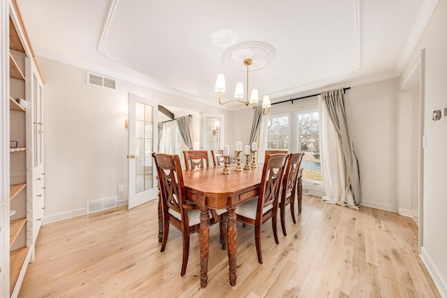 dining space featuring light wood-style floors, baseboards, visible vents, and a notable chandelier