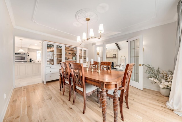 dining room featuring an inviting chandelier, light wood-style flooring, visible vents, and ornamental molding