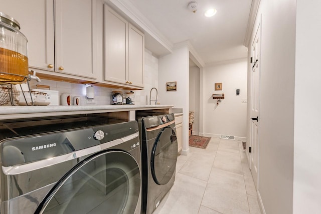 laundry area with light tile patterned flooring, baseboards, washer and dryer, ornamental molding, and cabinet space