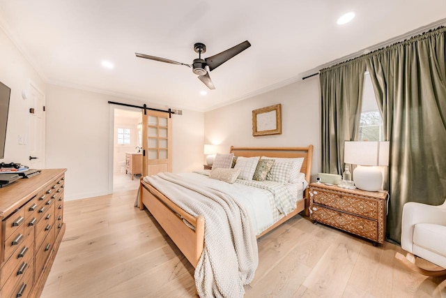 bedroom with ornamental molding, a barn door, and light wood finished floors