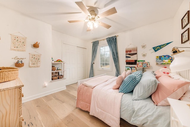 bedroom featuring ceiling fan, a closet, light wood-type flooring, and baseboards