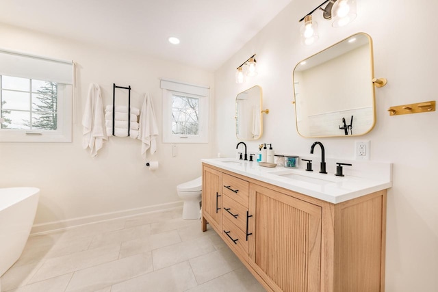 full bathroom with a soaking tub, a sink, baseboards, and double vanity