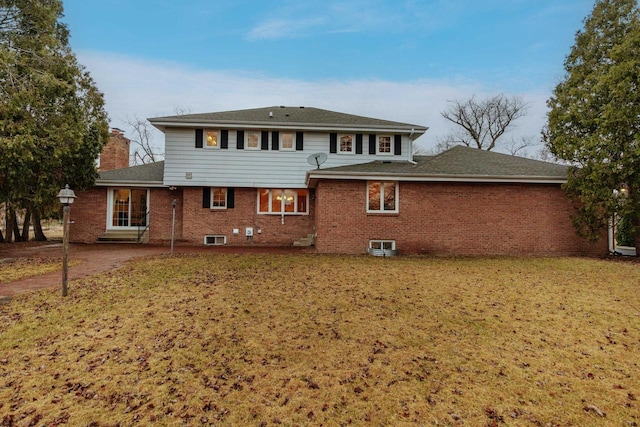 back of property featuring brick siding, a lawn, and a chimney