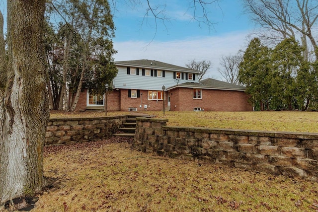 rear view of house featuring brick siding and a lawn